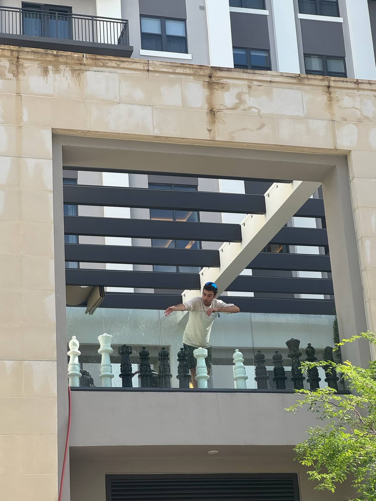 Vista co-founder Eliot De Paz working along the glass railing of an amenity terrace at a South Florida property, stained stone facade above him