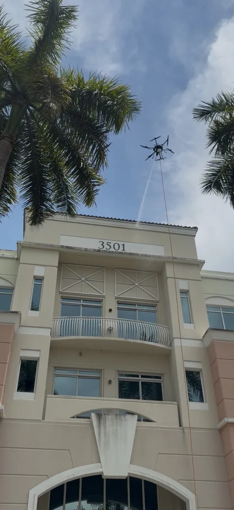 Vista Drone Cleaning industrial drone in flight beside a Miami commercial building facade during a wash
