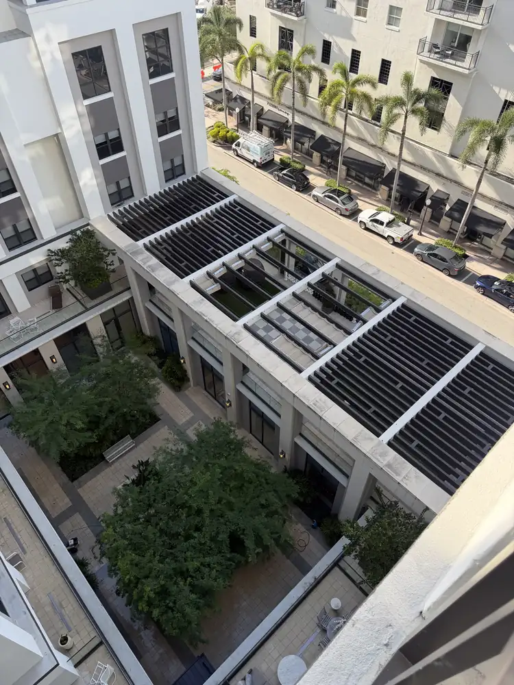 Aerial view of a Miami mid-rise commercial stone courtyard before a drone facade wash