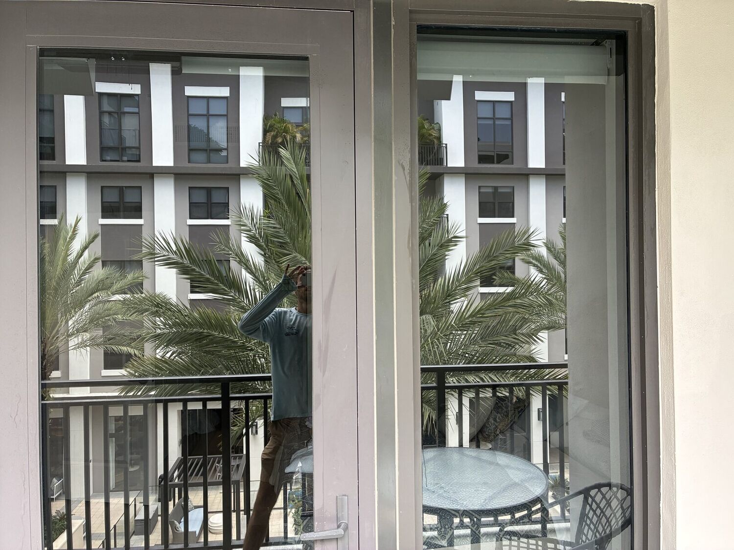 Technician cleaning exterior high-rise glass overlooking the courtyard at the Belmont Village high-rise in Coral Gables