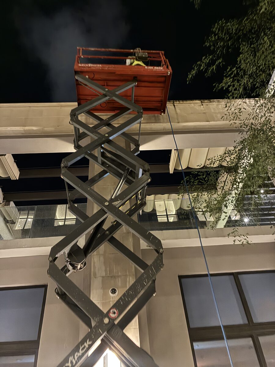 Crew on a lift cleaning the high-rise facade at night in Coral Gables