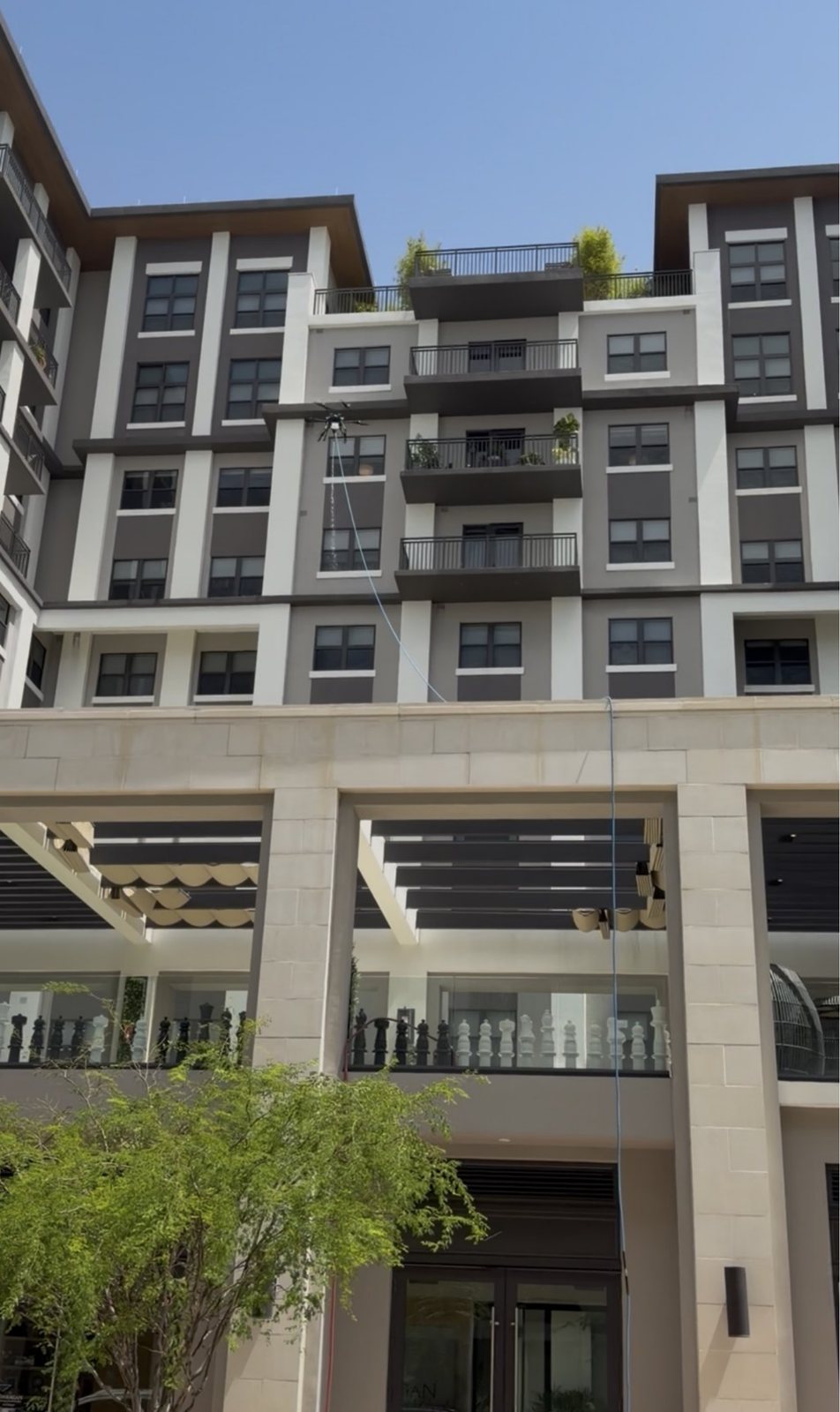 The Belmont Village courtyard facade in Coral Gables with the drone's tether running down past the chess terrace
