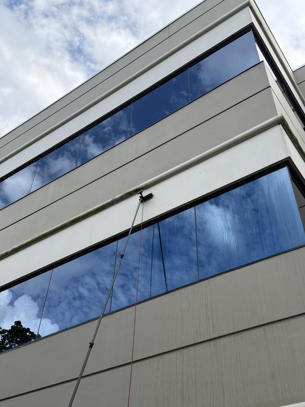 A water-fed pole reaching the upper ribbon windows of Cypress Plaza from the ground
