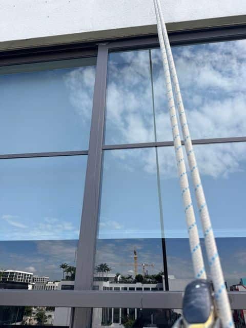 Clean glass reflecting the sky beside the rope access lines on Sentral Wynwood